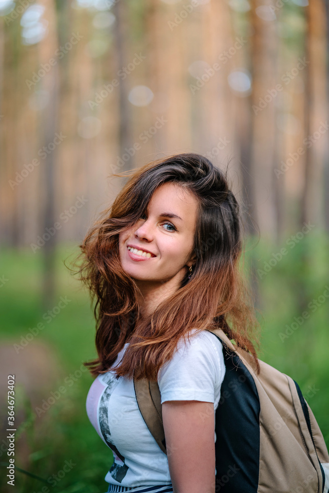Portrait of a woman with long hair and backpacks Hiking in a pine forest, tourism and banner for healthy recreation, copy space Portrait of a woman with long hair and backpacks Hiking in a pine forest, tourism and banner for healthy recreation, copy space