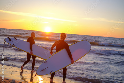 Φωτογραφία Unrecognizable surfers entering waving sea