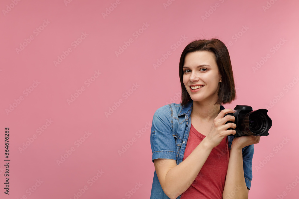 Portrait of young female photographer isolated on pink background with copy space. Photographer with professional camera taking photo in photo studio. Profession, occupation, self-employment. Portrait of young female photographer isolated on pink background with copy space. Photographer with professional camera taking photo in photo studio. Profession, occupation, self-employment.