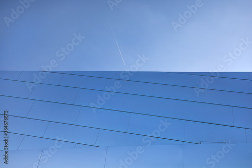 Fassade aus Glas mit Flugzeug im blauen Himmel