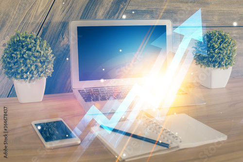 Computer on desktop with point up arrows hologram. Double exposure. Concept of success.