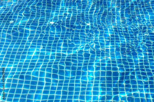 Ripples in the pool that reflect the sun Water surface details Is a bright blue background © wutthiphat