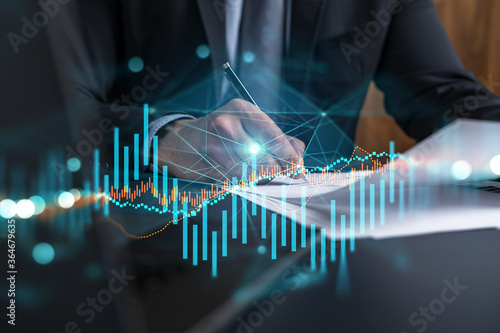 Businessman in suit signs contract. Double exposure with forex graph hologram. Man signing brokerage agreement. Financial market analysis and investment concept. photo