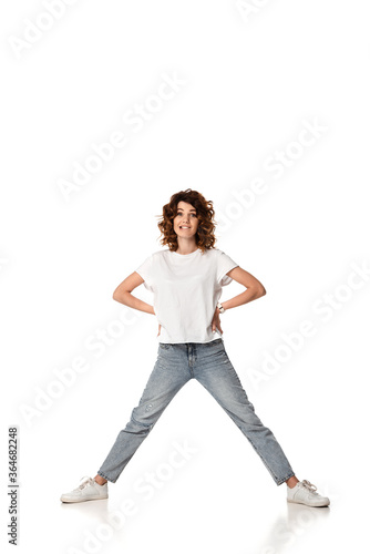 emotional woman standing with hands on hips and biting lips on white