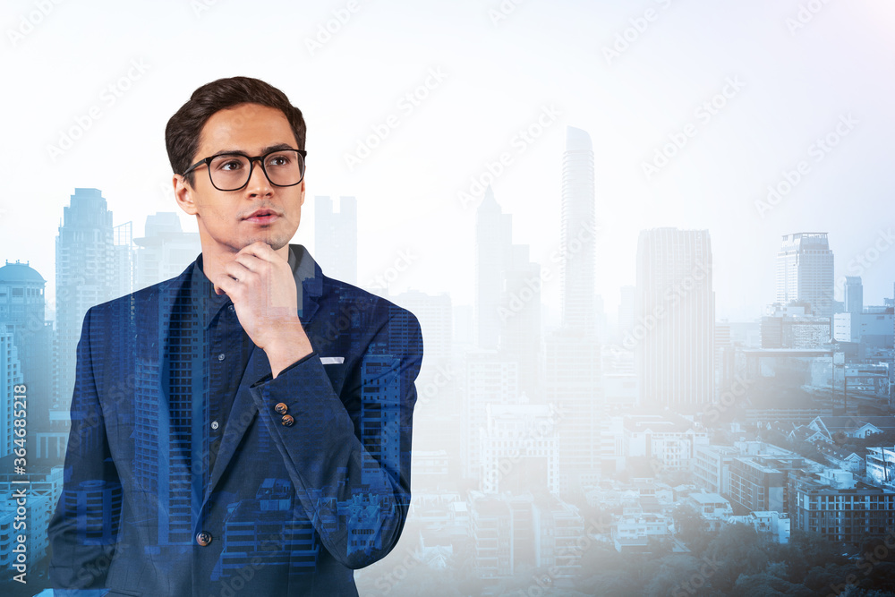 Young handsome businessman in suit and glasses dreaming about new career opportunities after MBA graduation. Bangkok on background. Double exposure.
