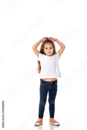cute kid in white t-shirt and jeans looking at camera on white