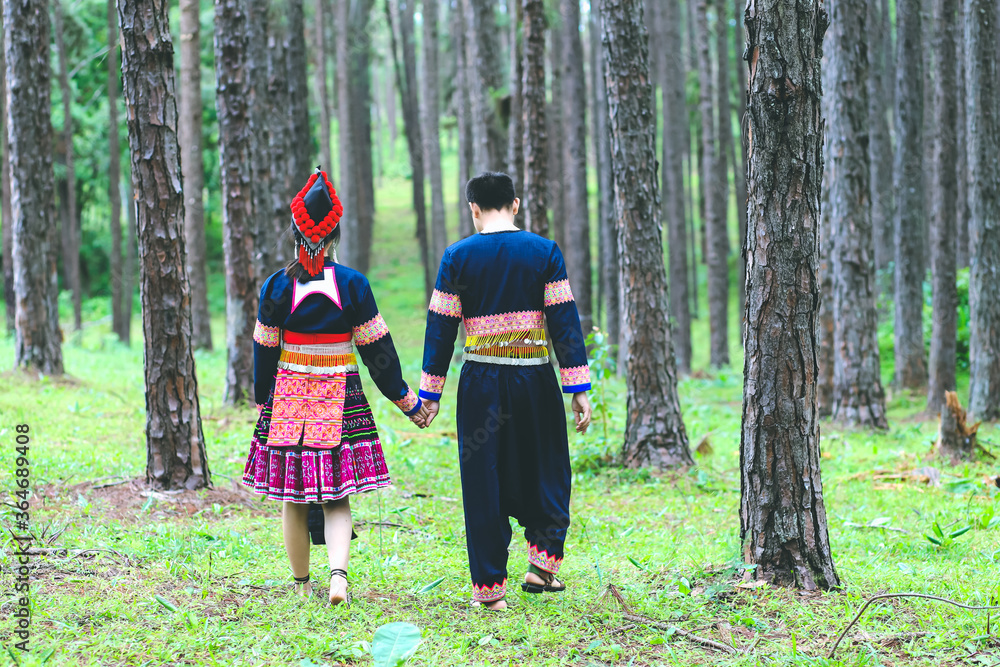 Couple hmongs holding hands and walking in the pine wood, Man and woman in Hmong clothes
