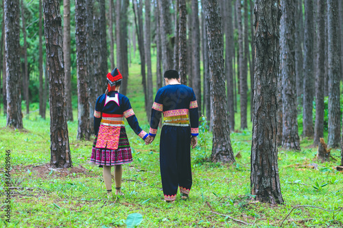 Couple hmongs holding hands and walking in the pine wood, Man and woman in Hmong clothes