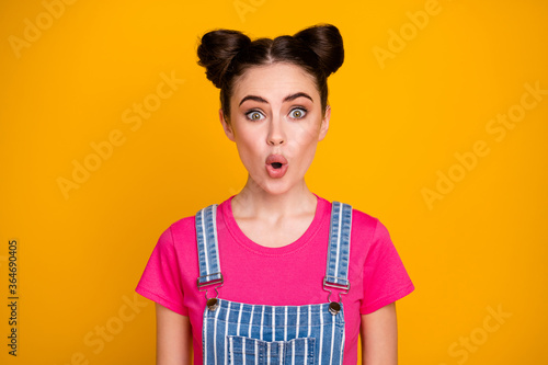 Photo of pretty amazed brunette lady teenager good mood open mouth listen cool news wear casual striped denim overall magenta t-shirt isolated vivid yellow color background