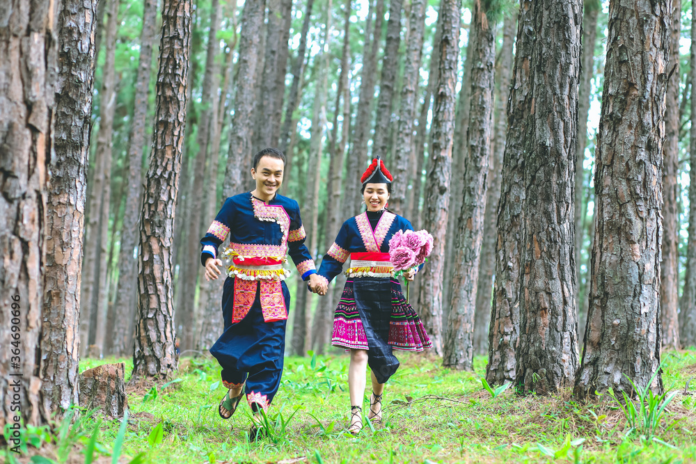 Fototapeta premium Couple hmongs holding hands and running in the pine wood, Man and woman in Hmong clothes