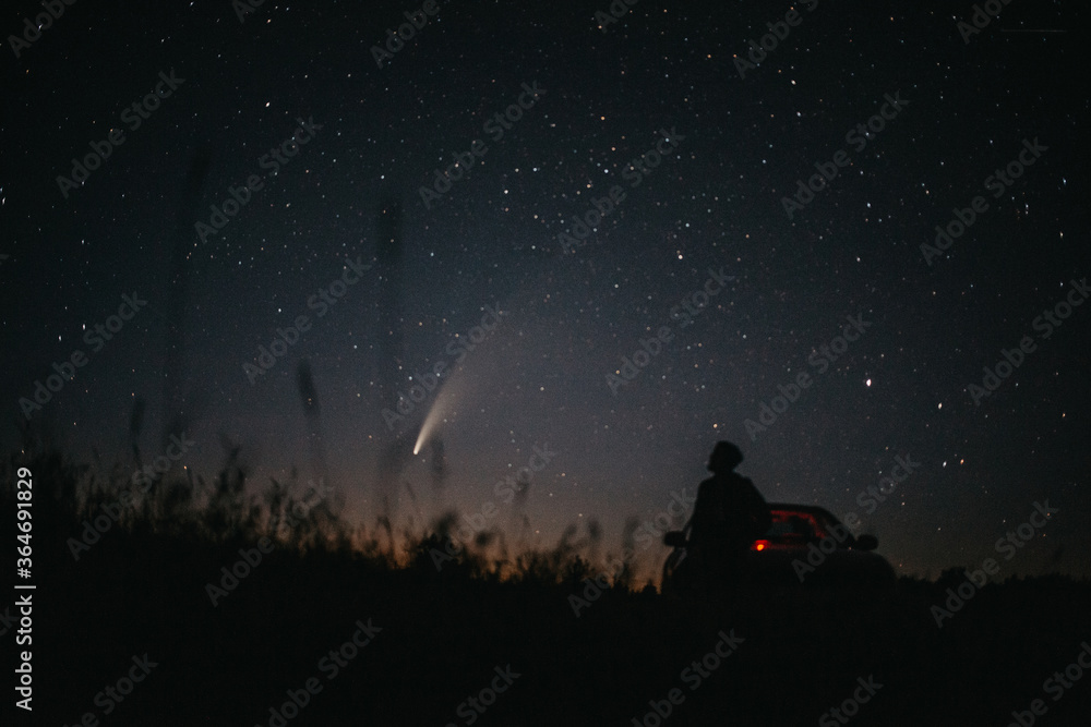 Young man on the background of the starry sky and comet NEOWISE. Comet C / 2020 F3 NEOWISE Observation - obrazy, fototapety, plakaty 