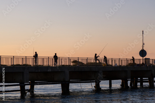 fishermen fishing with fishing rods on a pier at sunrise