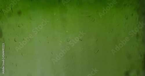 Water drops on green glass, blurred background. Texture