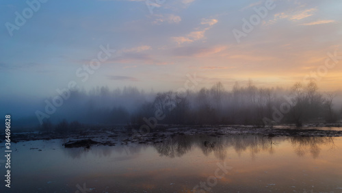 Sunset and forest lake, colorful dawn in the countryside, landscape with reflection in the water and rising fog.