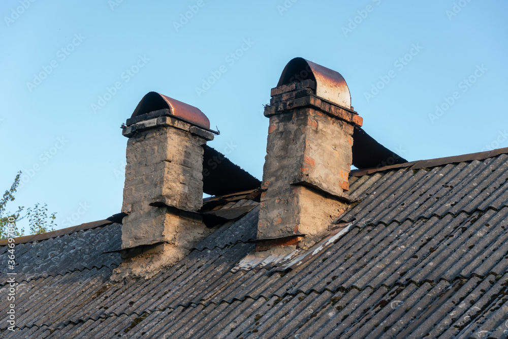 Two chimneys on the roof of the house close up against the blue sky Two chimneys on the roof of the house close up against the blue sky