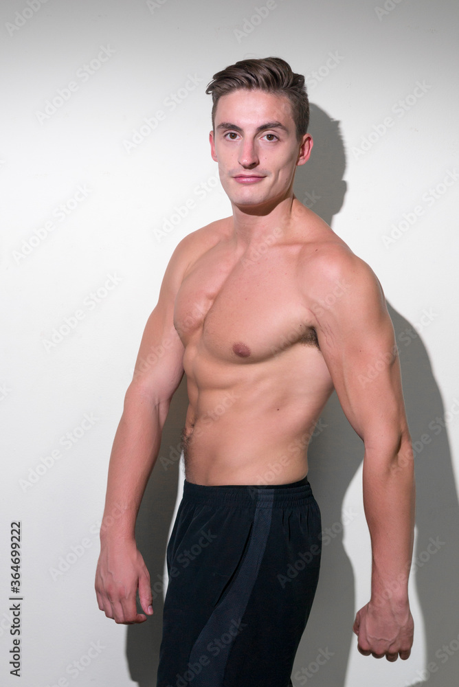 Portrait of young handsome muscular man flexing shirtless