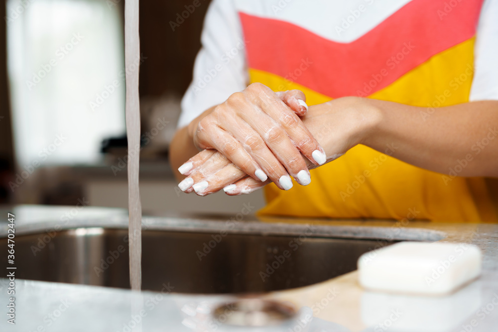Close up of a woman washing her hands in a kitchen sink