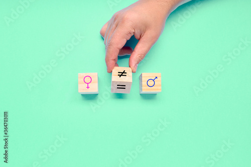 Hand turns a dice and changes a unequal sign to a equal sign between symbols of men and women