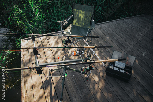 Young fisherman fishing on lake or river. Picture of fishing rods on river or lake shore. Empty place without people. Full equipmentfor fishing. Sunny day. photo