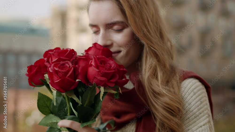 Woman hands bringing roses to face. Cheerful girl smelling flowers outdoors Woman hands bringing roses to face. Cheerful girl smelling flowers outdoors