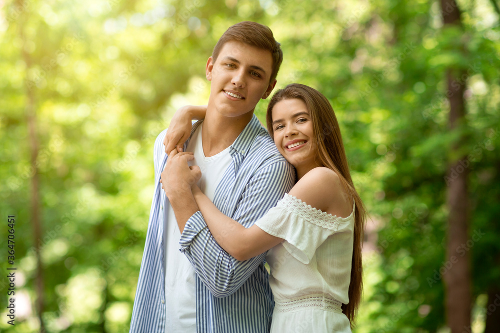 Affectionate girl hugging her boyfriend at park in summertime Affectionate girl hugging her boyfriend at park in summertime
