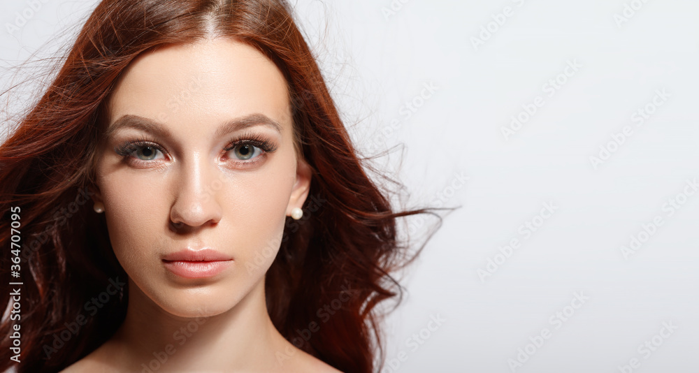 Fototapeta premium Studio glamor portrait of a beautiful woman with luxurious hair on a light background.