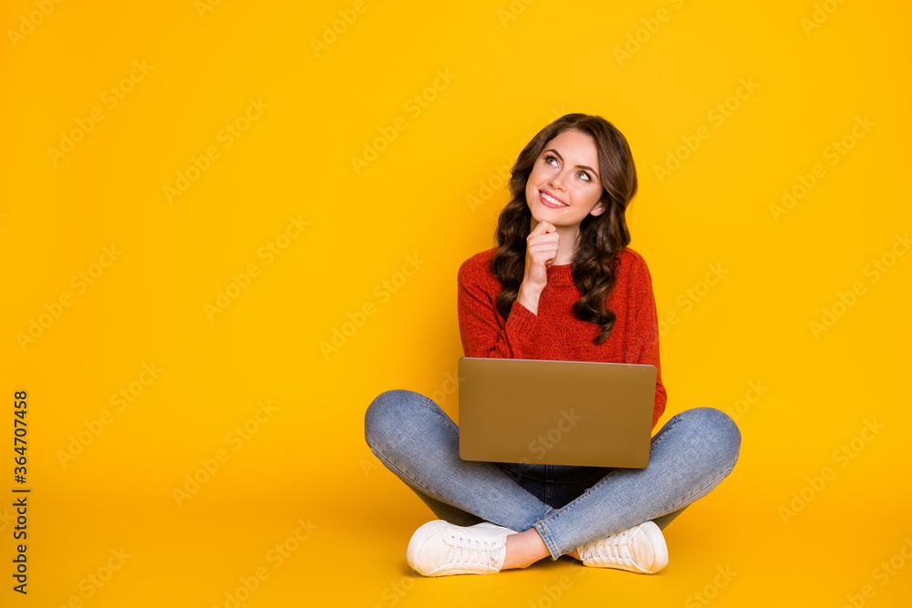 Photo of smart curious student in red pullover using netbook to write email to her friend making up story isolated over yellow background with copy space Photo of smart curious student in red pullover using netbook to write email to her friend making up story isolated over yellow background with copy space