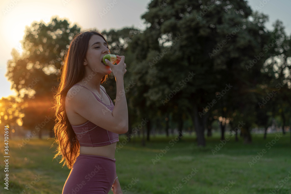 Young girl in sports wear eating green apple.