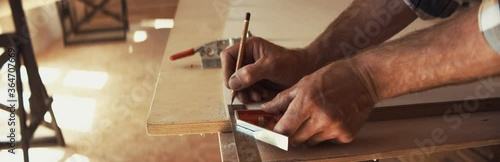 Caucasian male marking plywood while building a canoe in his workshop. Boat making hobby, small business owner. Shot on RED Dragon