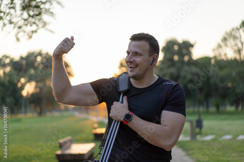 Fototapeta Naklejka Na Ścianę i Meble -   Attractive Man walking in a park after workout, wearing sport bag.