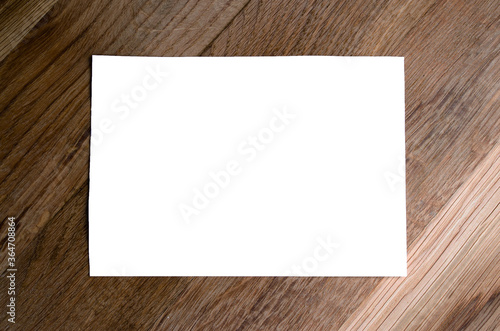White sheet of paper on a wooden background. Mock up
