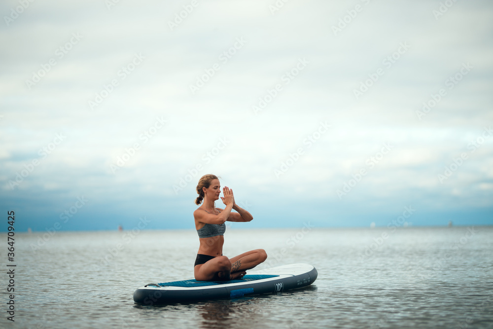 Fototapeta premium Woman practicing yoga on the paddle board in the morning