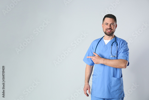 Portrait of mature doctor against light background