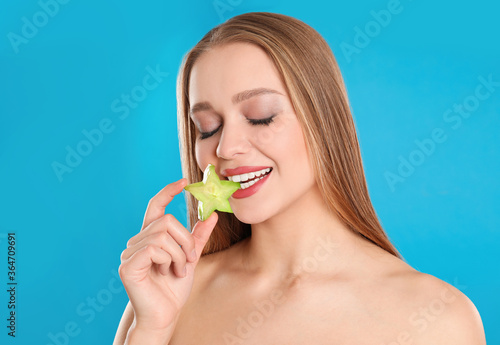 Young woman with cut carambola on blue background. Vitamin rich food