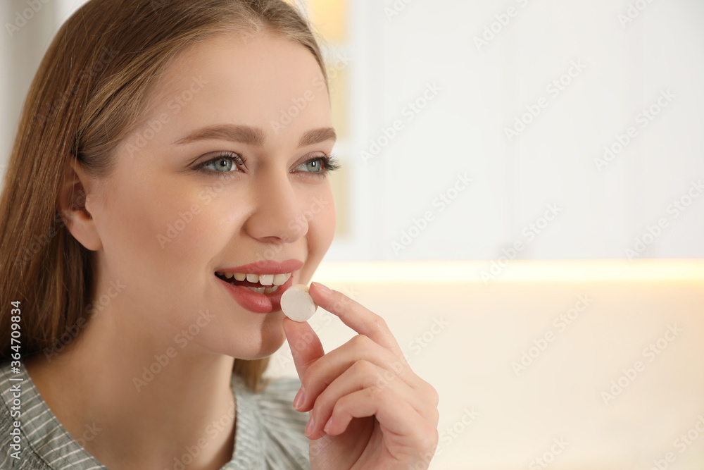 Young woman taking vitamin pill on light background. Space for text Young woman taking vitamin pill on light background. Space for text