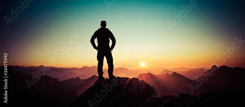 Man reaching summit enjoying freedom and looking towards mountains sunrise. Allgau Alps, Bavaria, Germany and Tyrol Austria.