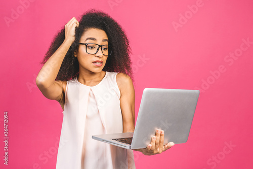 Shocked amazed african american black business or student woman, posing isolated on pink background. Mock up copy space. Working on laptop pc computer.