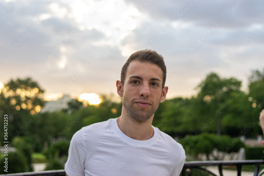 Photo of a young and attractive man standing in the park with very modern clothes Photo of a young and attractive man standing in the park with very modern clothes