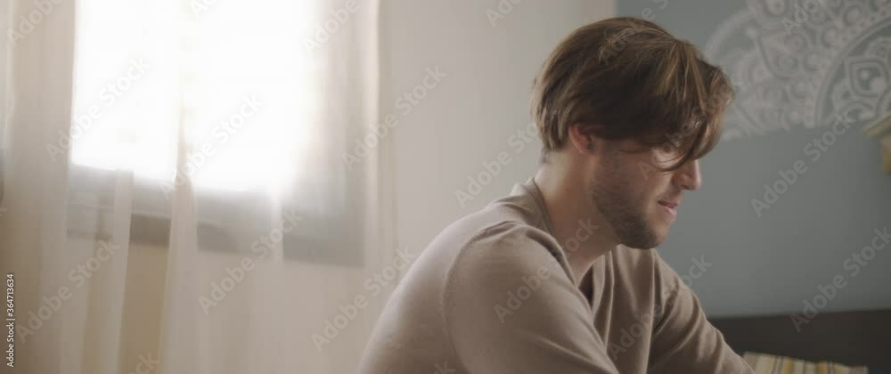 A young man sitting on bed, working from home. Close up, slow motion. BMPCC 4K A young man sitting on bed, working from home. Close up, slow motion. BMPCC 4K
