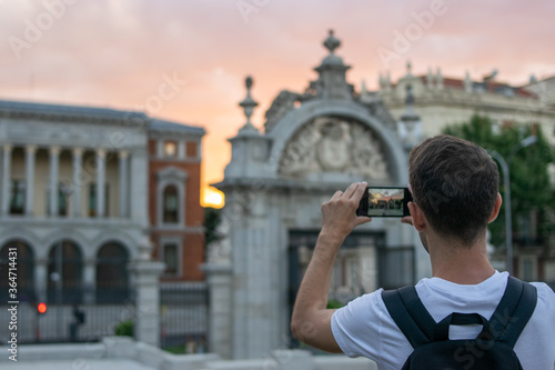 Madrid, Spain / July 13 2020 / Photo of an attractive guy next to Alcala gate in Madrid during sunset	
