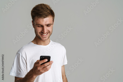 Portrait of handsome happy man smiling and using mobile phone