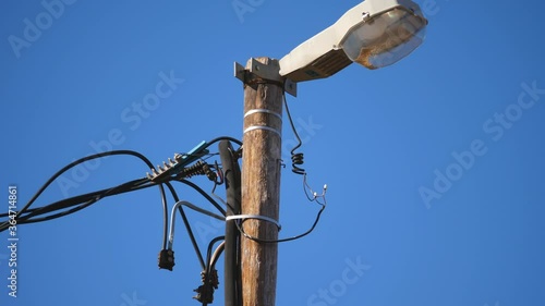 Street light in poor condition with exposed electrical wiring against blue sky background photo