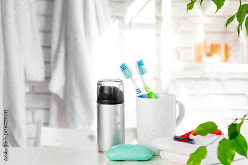 White cup with toothbrushes and towels in bathroom