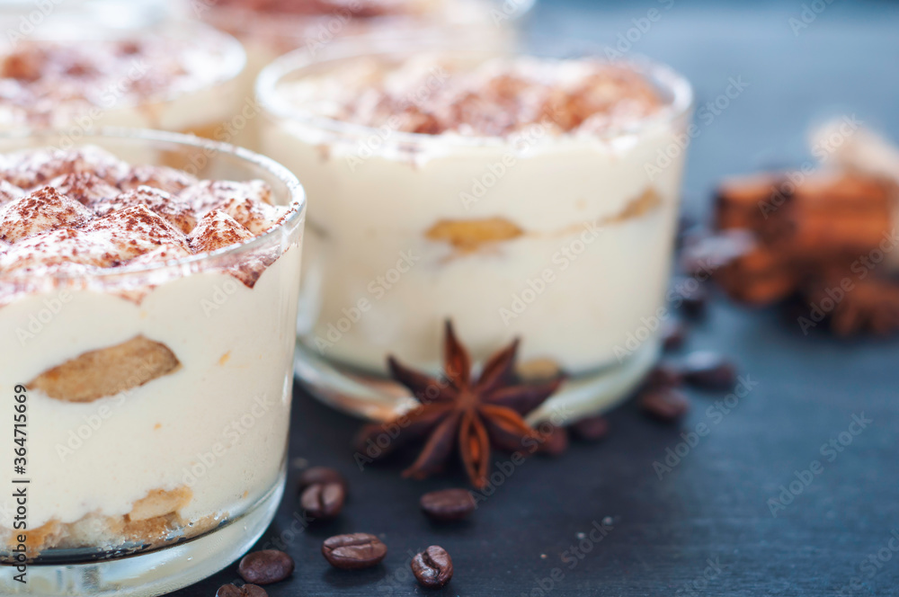 exquisite tiramisu in glasses decorated with cocoa powder on a dark background exquisite tiramisu in glasses decorated with cocoa powder on a dark background