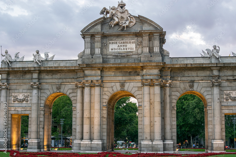 Obraz premium Madrid, Spain / July 13 2020 / Photo of an attractive guy next to Alcala gate in Madrid during sunset 