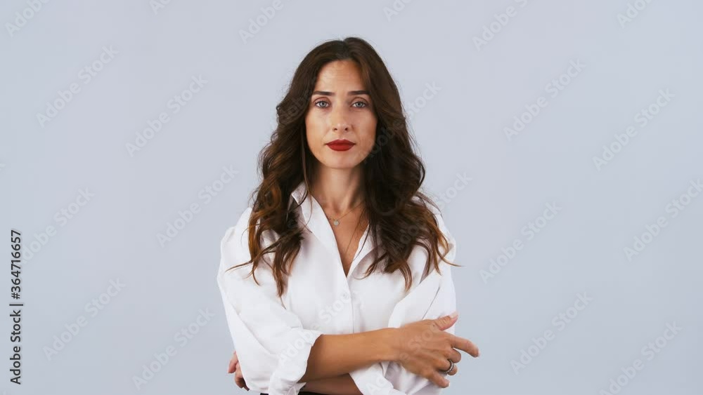 Young brunette girl in white shirt is imitating zipping her mouth shut and throwing out the key. Keep a secret. Posing on gray background. Close up Young brunette girl in white shirt is imitating zipping her mouth shut and throwing out the key. Keep a secret. Posing on gray background. Close up