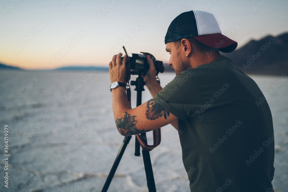 Skilled male travel blogger shooting film about natural landscape of Badwater basin work during expedition, tourist photographer taking pictures of scenic sunset in Death Valley during summer journey
