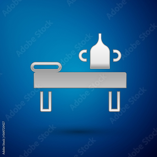 Silver Massage table with oil icon isolated on blue background. Vector.