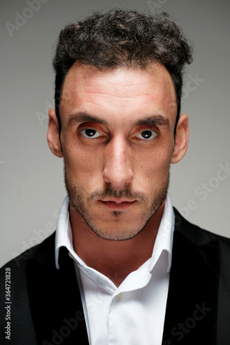 Close up portrait of a man 30-34 years old in a white shirt and a black jacket on a gray background.  © Oleg Samoylov