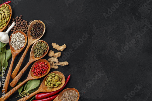 Wooden spoons with various spices on black background